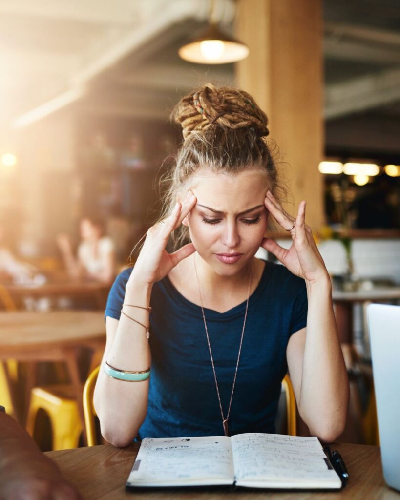 Woman rubbing her temples and distracted as she struggles to make sense of betrayal